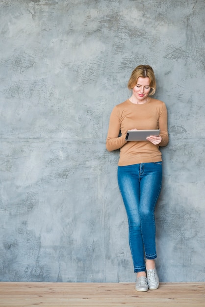 Kostenloses Foto blonde frau, die tablette an der wand verwendet