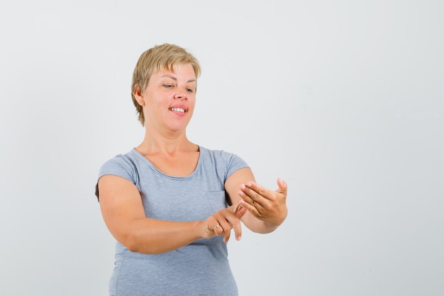 Blonde Frau, die vorgibt, etwas in hellblaues T-Shirt zu schreiben und fokussierte Vorderansicht zu schauen.