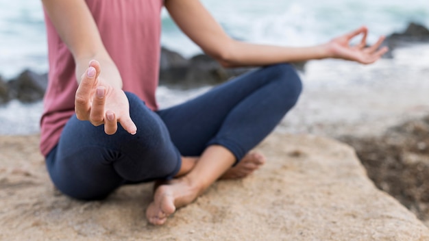 Blonde frau, die yoga am strand tut