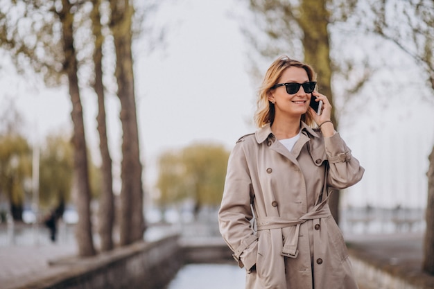 Blonde Frau im Mantel draußen im Park