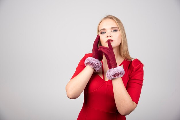 Blonde Frau im roten Cocktailkleid, die ihren Mund berührt.