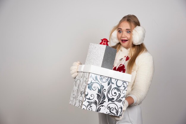 Blonde Frau im weißen Pullover, der Weihnachtsgeschenke betrachtet.