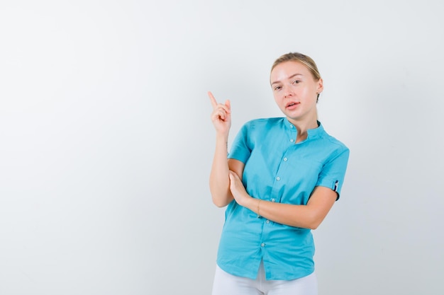 Blonde Frau in blauer Bluse zeigt auf die obere linke Ecke isoliert