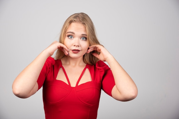 Blonde Frau in der roten Ausstattung, die Kamera betrachtet.