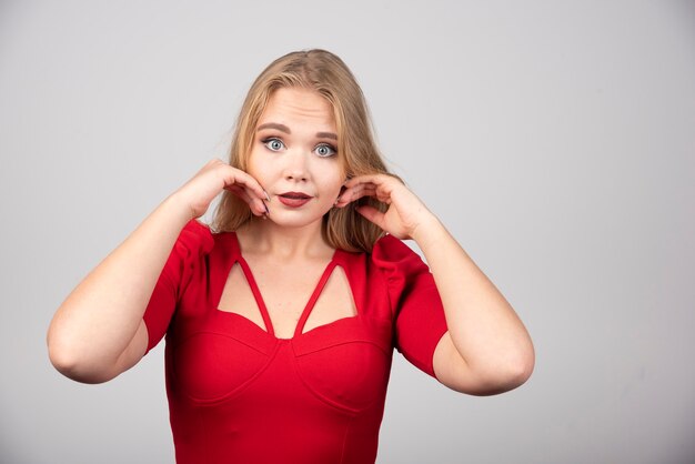 Blonde Frau in der roten Ausstattung, die Kamera betrachtet.