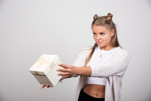 Blonde Frau in Winterausstattung mit Geschenkbox.