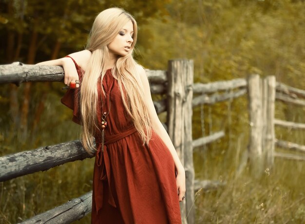 Blonde Frau mit einem braunen Kleid posiert im Freien