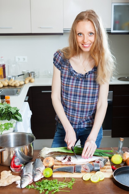 Blonde Frau schneidet rohen Fisch