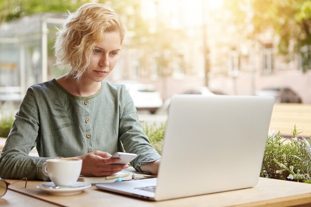 Blonde Frau sitzt mit Laptop im Café
