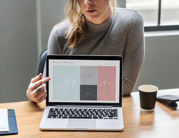 Blonde Frau zeigt auf einen Laptop-Bildschirm