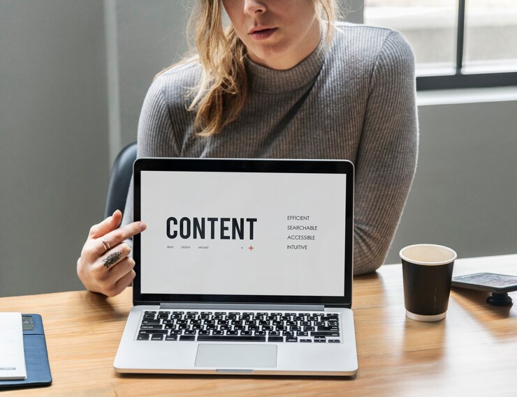 Kostenlose Foto blonde frau zeigt auf einen laptopbildschirm