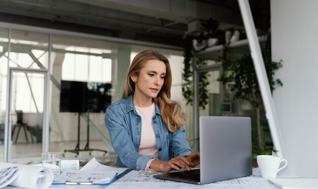 Blonde Geschäftsfrau, die an ihrem Laptop arbeitet