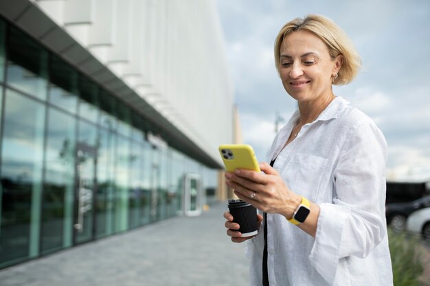 Blonde Geschäftsfrau, die ihr Telefon überprüft