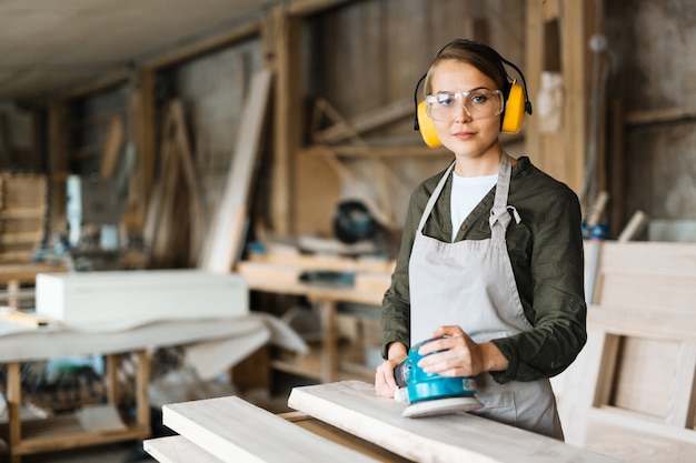 Blonde Handwerkerin mit elektrischer Schleifmaschine