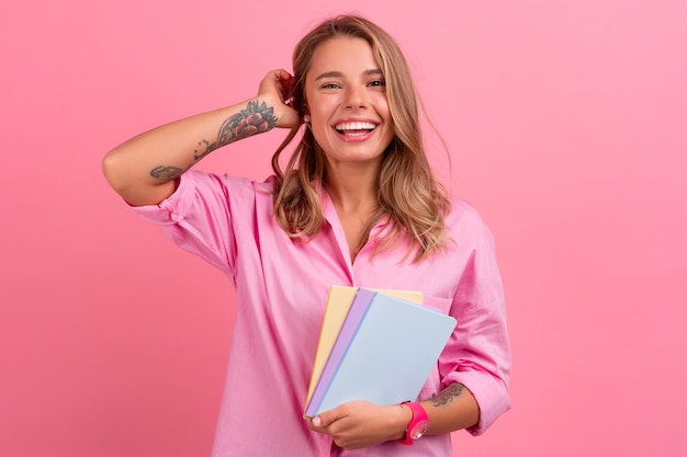 Blonde hübsche Frau im rosa Hemd lächelt, hält Notizbücher in der Hand