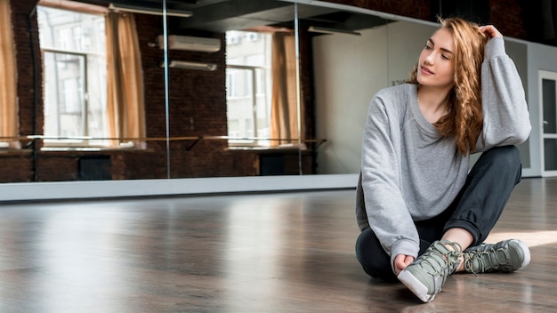 Kostenloses Foto blonde junge frau, die auf massivholzboden vor spiegel sitzt