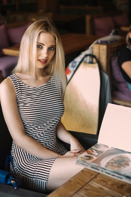 Blonde junge Frau, die im Restaurant sitzt