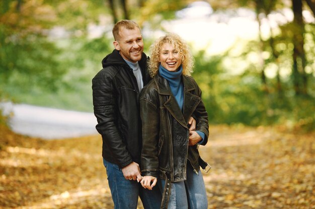 Blonde lockige Frau und Mann stehen im Herbstwald und umarmen sich