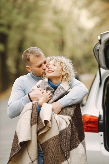 Blonde lockige Frau und Mann stehen im Herbstwald und umarmen sich