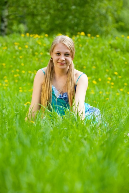 Blonde Mädchen sitzt im Gras