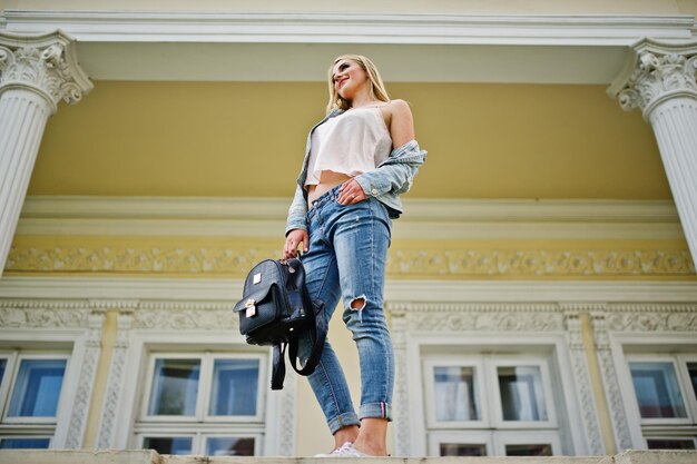 Blonde Mädchen tragen Jeans mit Rucksack gegen Vintage-Haus gestellt