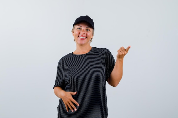 Blonde reife Frau in einem schwarzen T-Shirt und einer schwarzen Mütze