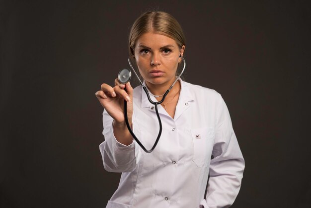 Blonde Ärztin mit einem Stethoskop, das den Patienten überprüft.