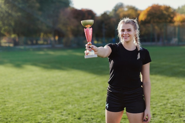 Blonde schöne Frau, die eine Sporttrophäe anhält