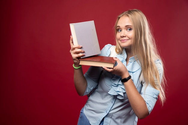 Blonde Studentin hält ihre Bücher und fühlt sich glücklich.