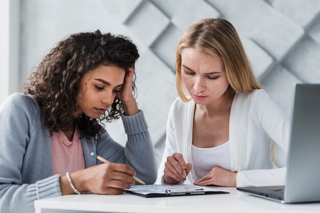 Blonde und ethnische Mitarbeiter, die an der Arbeitsaufgabe denken