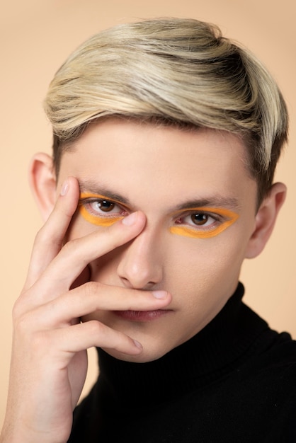 Blonder Mann, der orange Eyeliner trägt