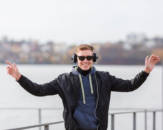 Kostenloses Foto blonder mann des mittleren schusssmiley, der draußen musik hört