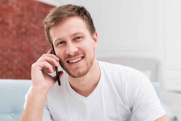 Blonder Mann des smiley, der am Telefon spricht