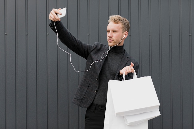 Blonder Mann im Schwarzen, der ein selfie mit Smartphone nimmt