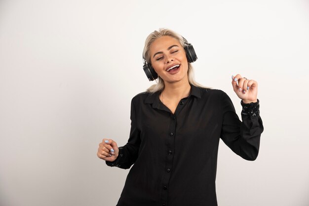 Blondes Frauenhörlied mit Kopfhörern auf weißem Hintergrund. Hochwertiges Foto