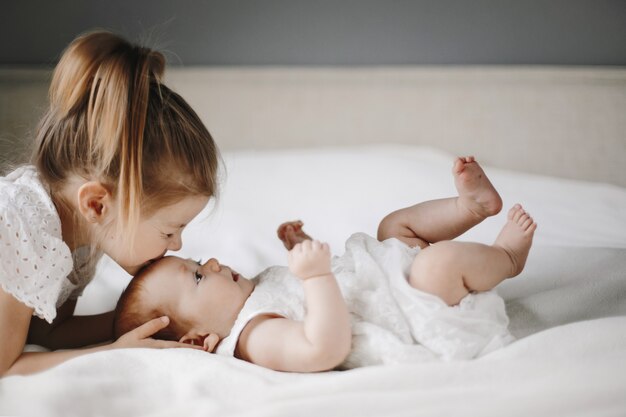 Blondes Kind auf der weißen Decke gekleidet in der weißen Kleidung