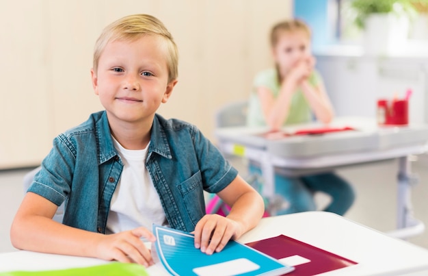 Kostenloses Foto blondes kind sitzt an seinem schreibtisch