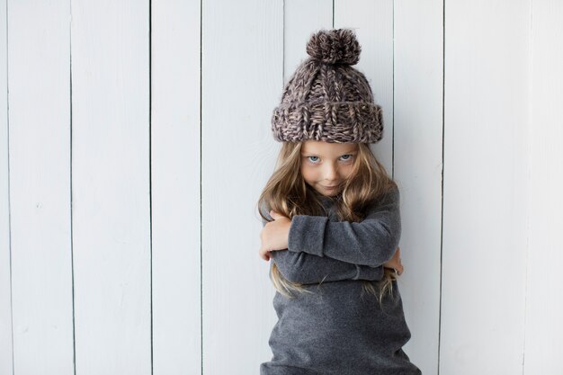 Blondes kleines Mädchen, das in der Winterkleidung aufwirft