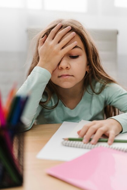 Blondes kleines Mädchen, das Kopfschmerzen beim Online-Unterricht hat