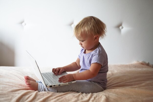 Blondes Kleinkind, das zuhause mit PC-Laptop spielt