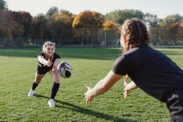 Blondes Mädchen, das einen Ball zu einem Mannschaftskameraden wirft