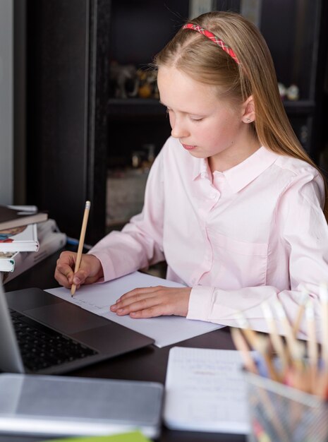 Blondes Mädchen, das Notizen in der Online-Klasse macht