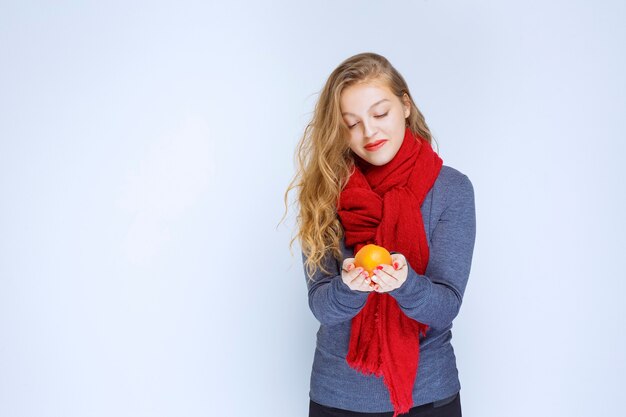 Blondes Mädchen, das orange Früchte hält und demonstriert.