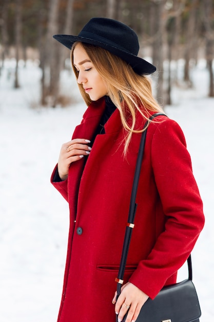 Kostenloses Foto blondes mädchen, das roten mantel auf einem schneebedeckten feld trägt