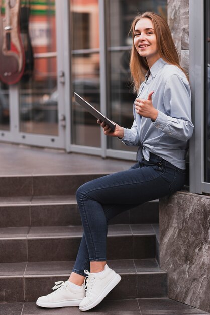 Blondes Mädchen der Seitenansicht, das eine Tablette hält