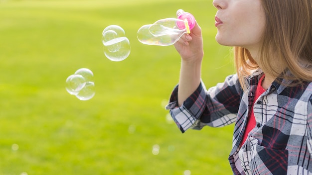 Blondes Mädchen der Seitenansicht, das Seifenblasen macht