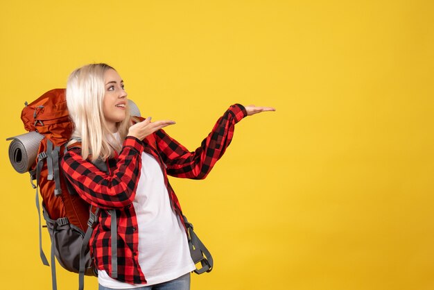 Blondes Mädchen der Vorderansicht mit ihrem Rucksack, der etwas zeigt