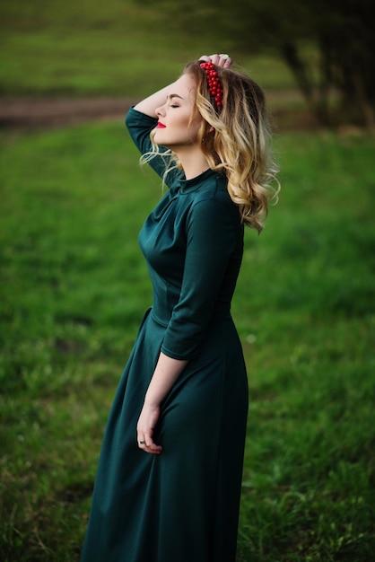 Blondes Mädchen der Yong-Eleganz im grünen Kleid auf dem Garten im Frühjahr