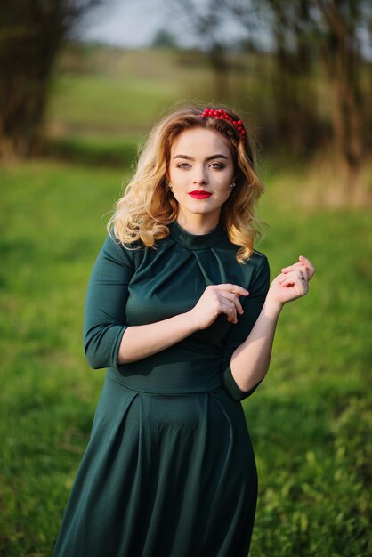 Blondes Mädchen der Yong-Eleganz im grünen Kleid auf dem Garten im Frühjahr