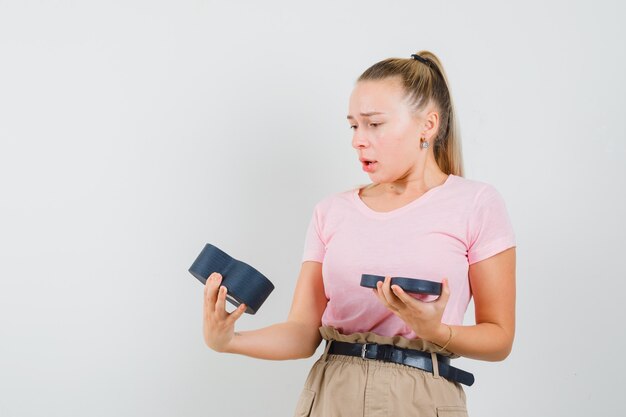 Blondes Mädchen im T-Shirt, Hosen, die leere Geschenkbox betrachten und enttäuscht schauen, Vorderansicht.